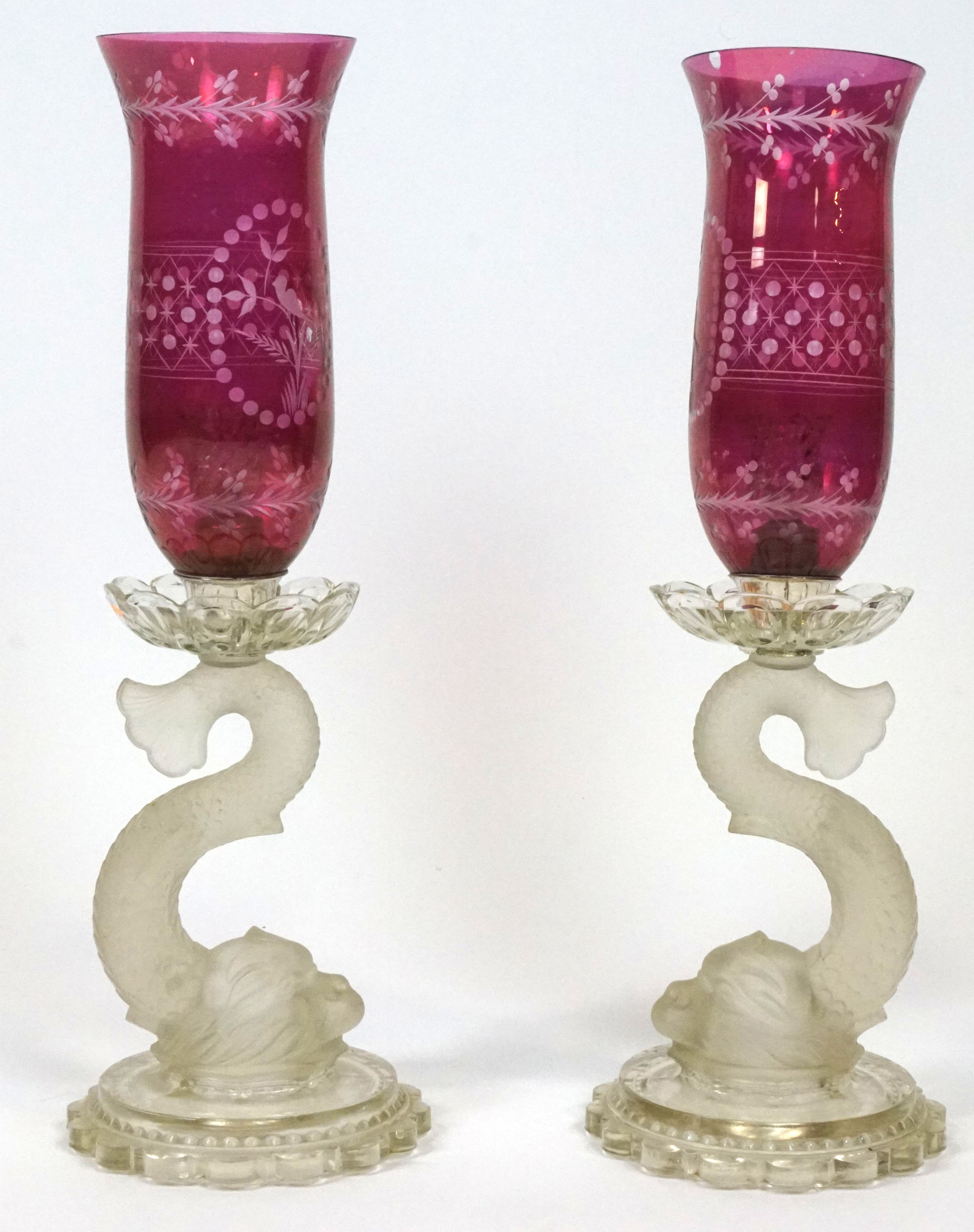 A pair of Baccarat dolphin candlesticks, each with engraved ruby-tinted engraved flared shades,