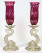 A pair of Baccarat dolphin candlesticks, each with engraved ruby-tinted engraved flared shades,