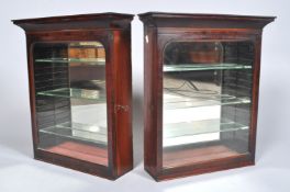 A pair of mahogany wall display cabinets with shaped cornice top over a glass door with shaped