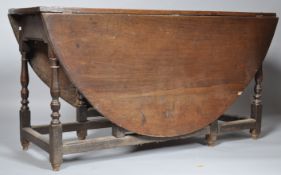 A 19th century oak oval drop leaf table on turned gate legs,