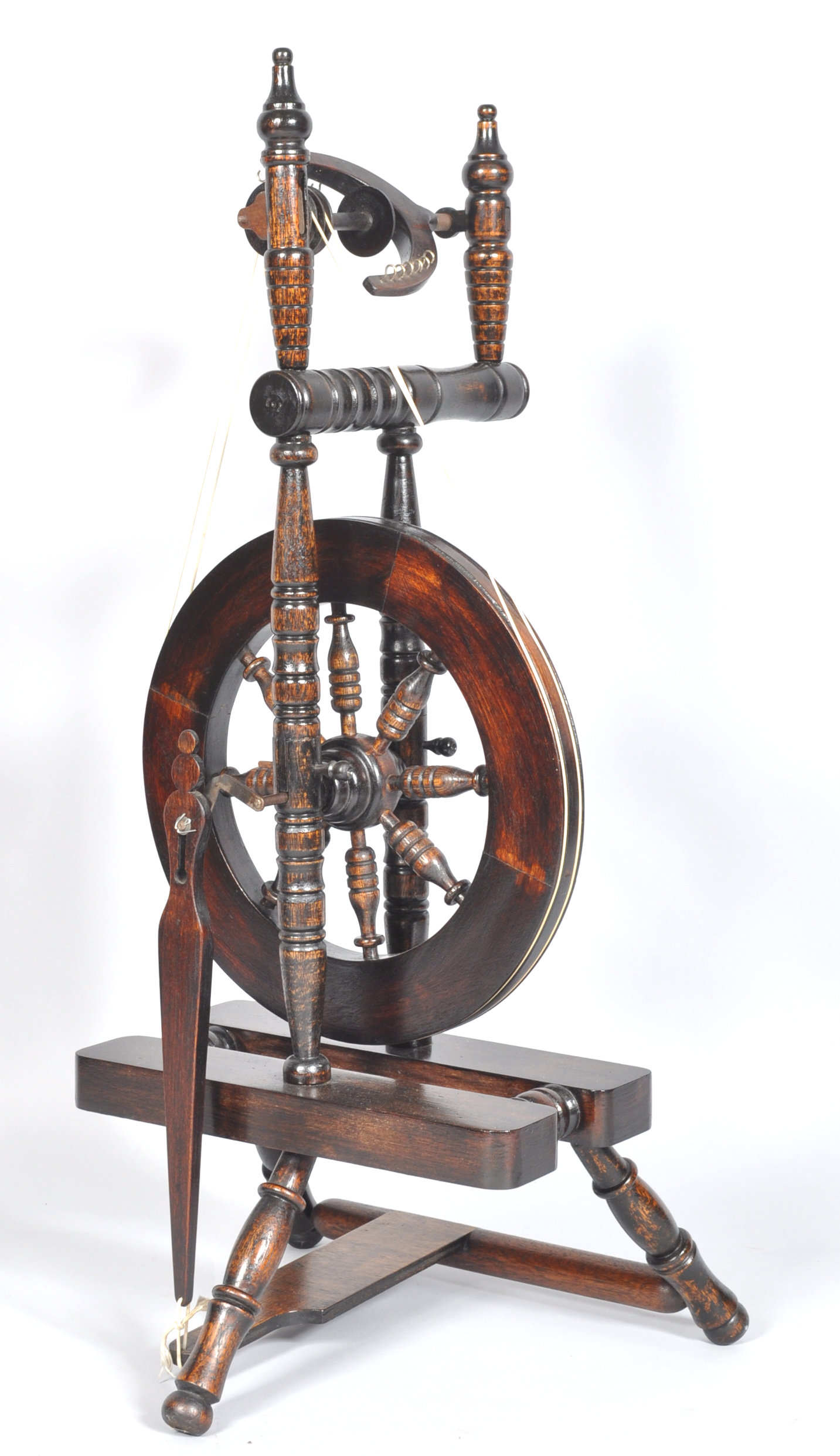 A contemporary castle style turned stained oak spinning wheel. Measures; 103cm.