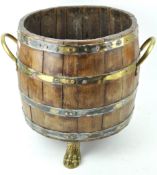 A staved and brass bound log basket with two handles on brass paw feet,