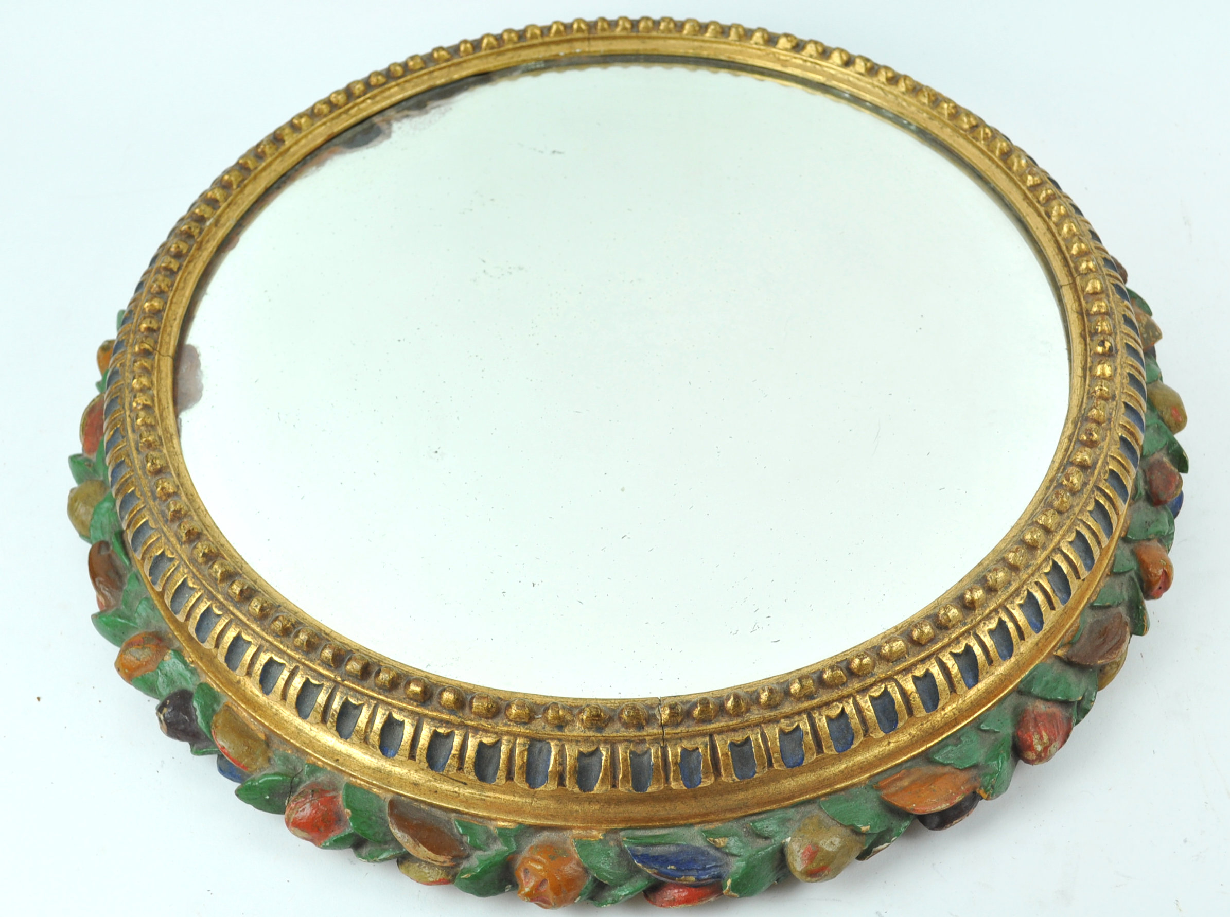 A round wall mirror in carved wood gilt painted frame,