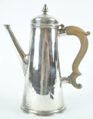 A silver coffee pot of tapered cylindrical form with urn topped raised cover and a plain spout