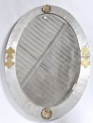 An Art Deco oval bevelled mirror in a broad beaten pewter frame,