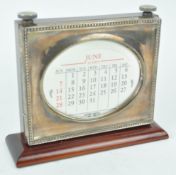 A silver mounted mahogany desk perpetual calendar