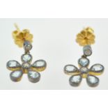 A yellow and white metal pair of drop earrings.