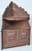 A late 19th Century angloindian style oak carved wall mounted corner cabinet having a single shelf