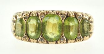 A yellow metal half hoop ring set with five graduated oval faceted cut peridot and interspaced with