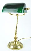 A brass desk lamp with adjustable rectangular green milk glass shade,