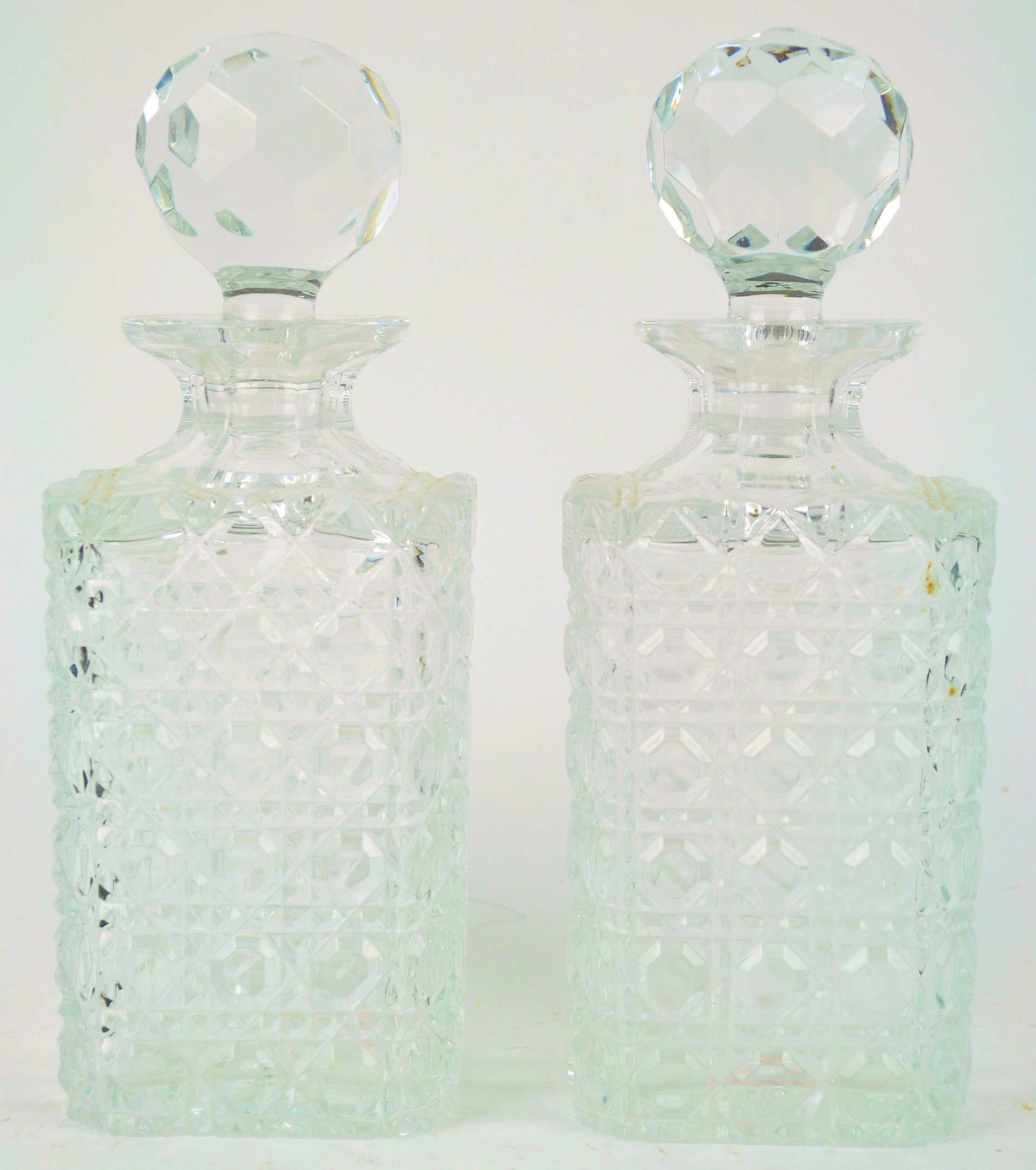 A pair of cut glass square decanters and stoppers, each with a star cut base,