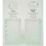 A pair of cut glass square decanters and stoppers, each with a star cut base,