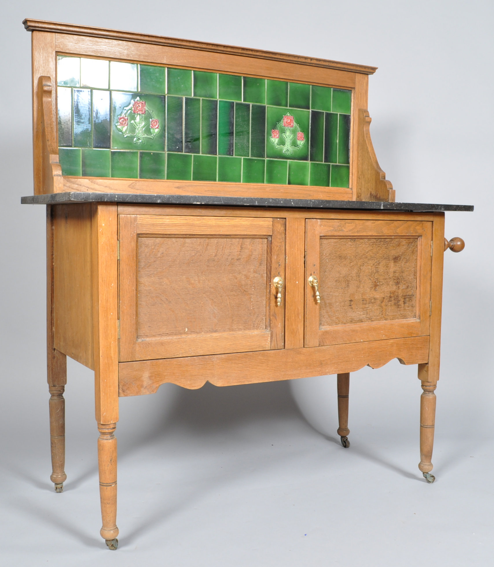 A 19th century oak washstand, with tiled back and marble top above two panelled doors,