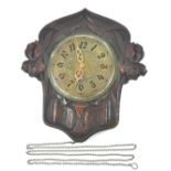An Art Nouveau style wall clock with brass dial, the carved oak case decorated with iris,