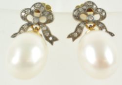 A yellow and white metal pair of drop earrings.