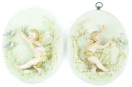 A pair of 19th century German bisque porcelain oval wall plaques of putti with doves,