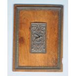 A mahogany panel with central bronze relief and frame,