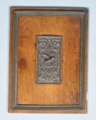 A mahogany panel with central bronze relief and frame,