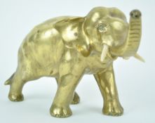 An Oriental polished bronze figure of an elephant with trunk aloft, signature to the underside,