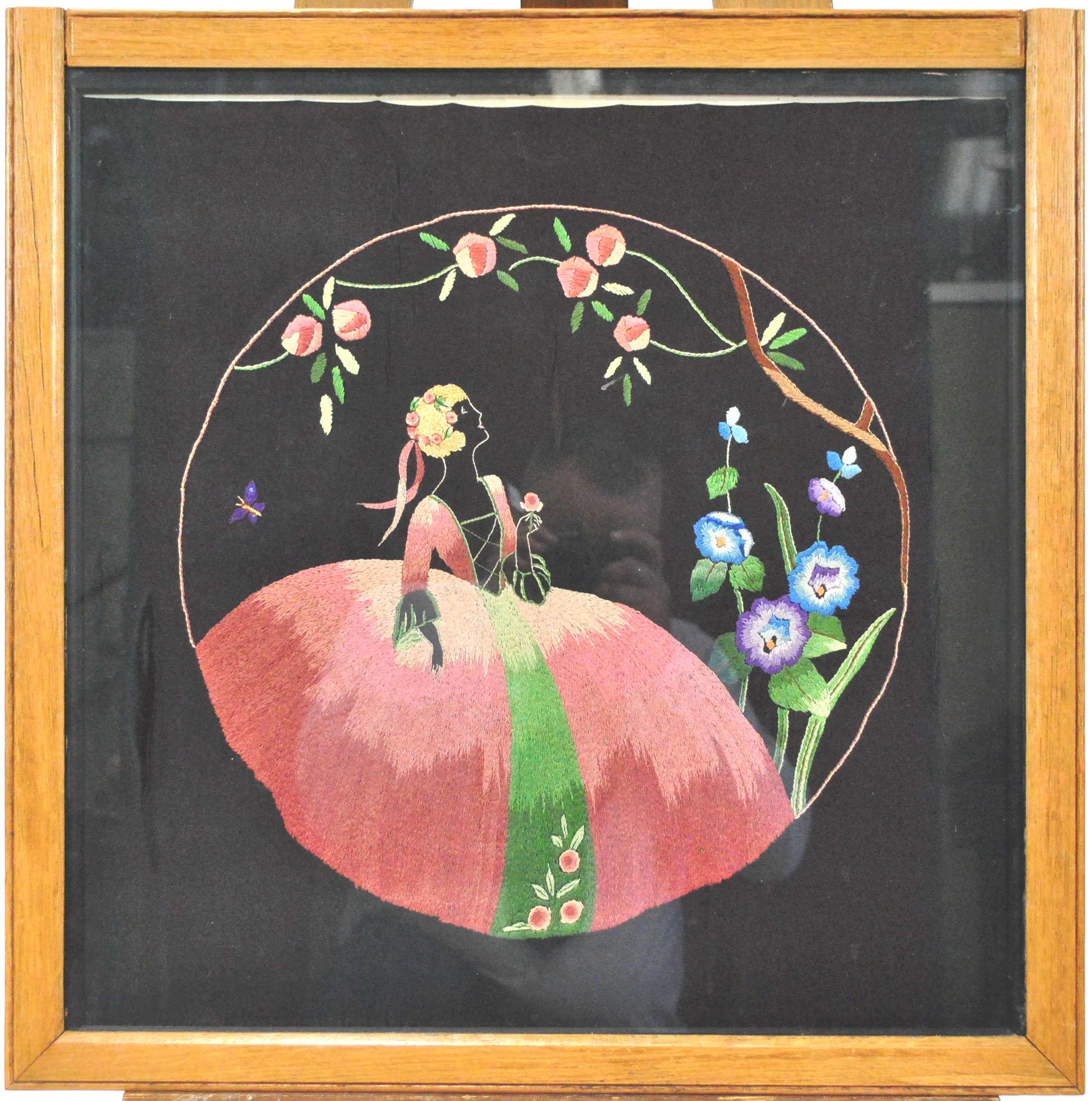 An Art Deco silk work of a lady in a crinoline dress, in a garden setting with roses and hollyhocks, - Image 2 of 2