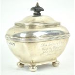 A silver tea caddy, of rounded rectangular form with domed hinged cover, raised on ball feet,