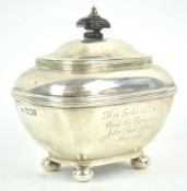 A silver tea caddy, of rounded rectangular form with domed hinged cover, raised on ball feet,