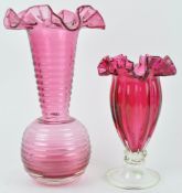 A large cranberry tinted vase with globular body and flared neck, terminating in a wide frill rim,