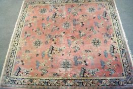 A Chinese style carpet with an overall pattern of repeating motifs on a pink ground