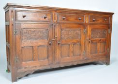 A carved oak sideboard with three drawers above three drawers above three panelled doors,