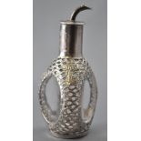 An Asian glass bitters bottle of dimpled triangular form, overlaid in a white metal sleeve,