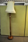 A 20th century turned wood standard lamp, having a shade atop a round plinth base,