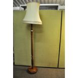 A 20th century turned wood standard lamp, having a shade atop a round plinth base,