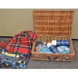 A wicker picnic hamper and two car rugs