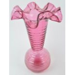 A large cranberry tinted vase with globular body and flared neck, terminating in a wide frill rim,