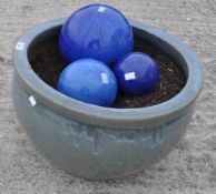 A blue glazed garden pot and three glazed balls