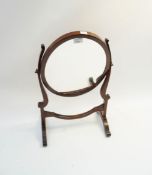 A mahogany swing mirror, of oval form,