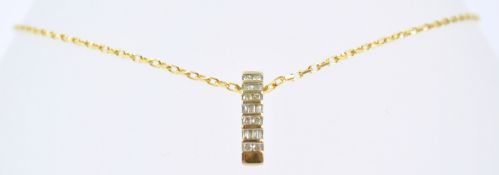 A yellow metal pendant set with round and baguette cut diamonds suspended from a trace link chain.