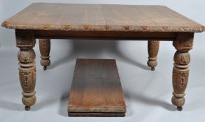 A Victorian oak wind out dining table with two extra leaves, with carved supports and border,