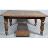 A Victorian oak wind out dining table with two extra leaves, with carved supports and border,