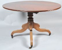 A 19th century mahogany oval tilt top table, on turned pedestal and splayed legs with brass casters,