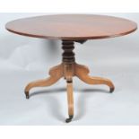 A 19th century mahogany oval tilt top table, on turned pedestal and splayed legs with brass casters,