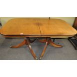 A mahogany twin pedestal dining table with one loose leaf,