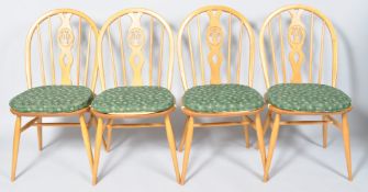A set of Ercol beech and elm feather back dining chairs in the blonde colourway each with pad seat.