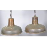 A pair of contemporary industrial copper pendant ceiling lights, finished with a patinated exterior,