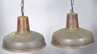 A pair of contemporary industrial copper pendant ceiling lights, finished with a patinated exterior,