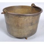 A 19th century bronze cylindrical footed cooking pot, with swing handle,