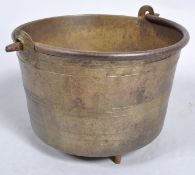 A 19th century bronze cylindrical footed cooking pot, with swing handle,