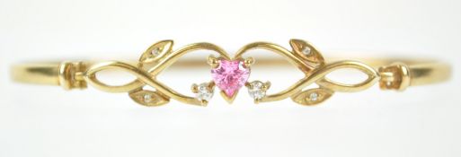 A yellow metal bangle principally set with a heart shaped pink cubic zirconia.