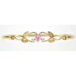 A yellow metal bangle principally set with a heart shaped pink cubic zirconia.