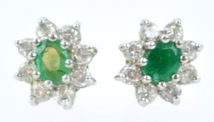 A yellow and white metal pair of emerald and cubic zirconia cluster stud earrings.